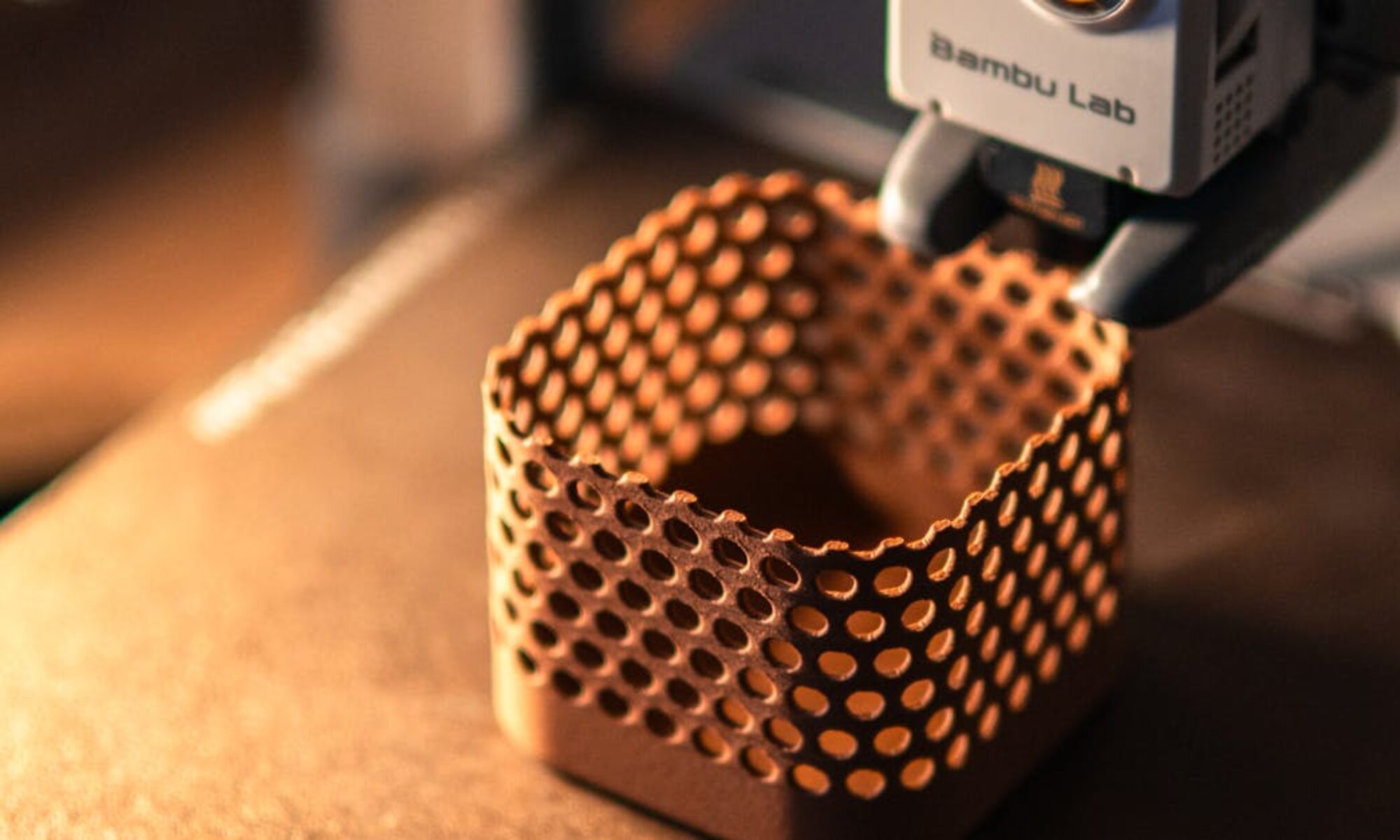 Close-up of a 3D printer creating a hexagonal object in a dimly lit workspace.